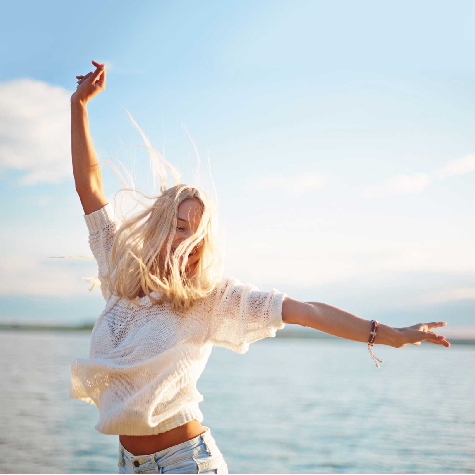 Frau die am Strand tanzt und Lebensfreude ausstrahlt.