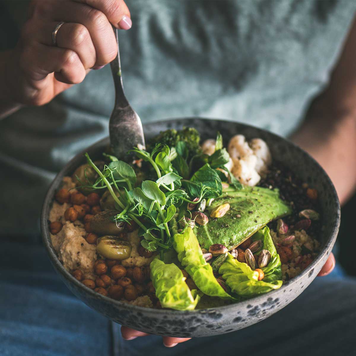 eine Nahaufnahme von einer Schüssel mit gesundem Essen die ein Mann isst.