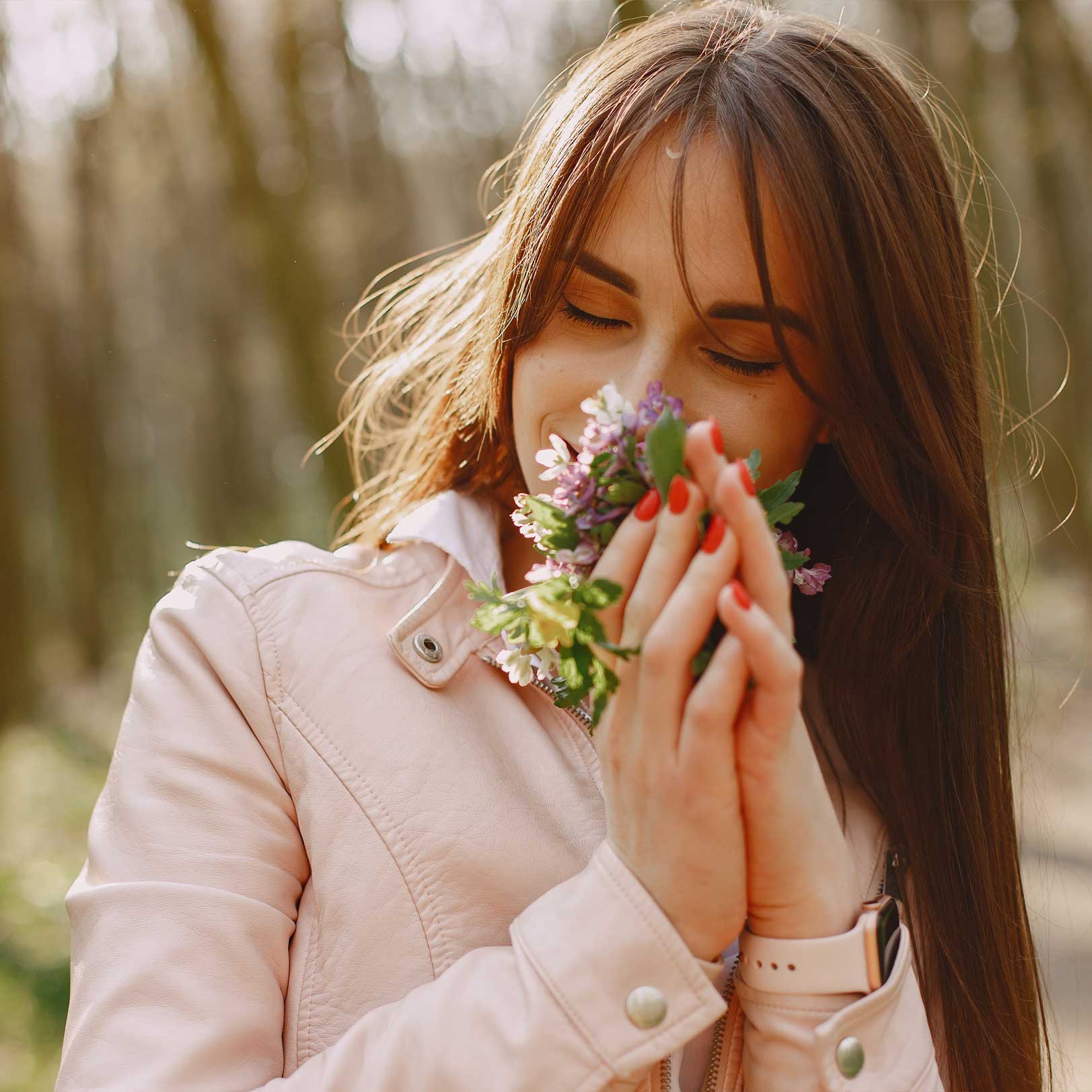 Frau riecht im Frühling an gepflückten Blumen 